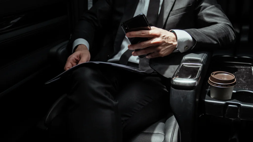 Professional chauffeur standing beside a luxury black car in Denver, ready for private or business transport